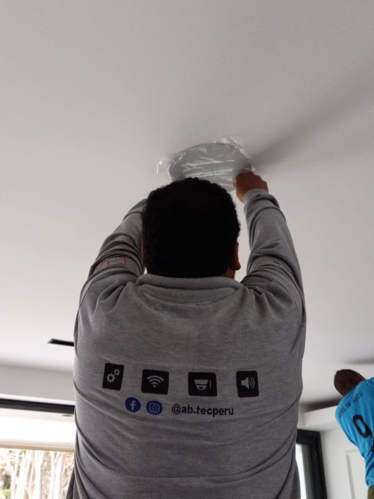 Técnico instalando un dispositivo inteligente en un techo.